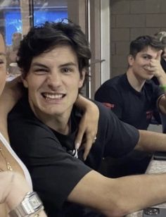 two people sitting at a table with drinks in front of them and one person standing behind the counter