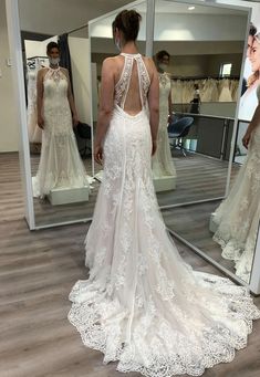 a woman in a wedding dress looking at herself in the mirror