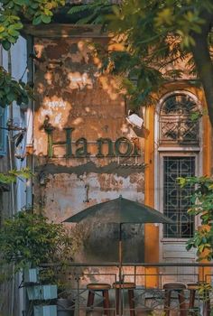 an old building with tables and umbrellas in front of the door that says hano