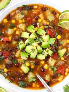 a white bowl filled with vegetable soup next to sliced avocado and cilantro