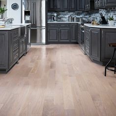 a large kitchen with gray cabinets and wood flooring is seen in this image from the front view