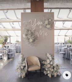 a chair sitting in front of a sign that says you and me with flowers on it