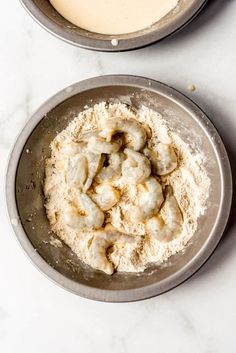 two pans filled with food sitting on top of a white counter next to each other