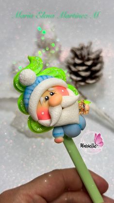 a hand holding a green and white flower with a santa clause on it's head