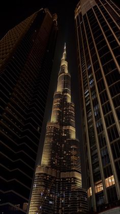 the burj building is lit up at night in front of other tall buildings