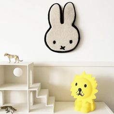 a white shelf topped with toys and a stuffed animal next to a wall mounted clock