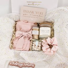 an open gift box with candles, cookies and marshmallows on a bed