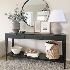 a black console table with two vases and a mirror