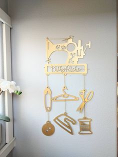 a metal wall hanging with scissors and other items on it's side, next to a window