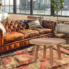 a living room with leather couches and a table in front of large windows overlooking the city