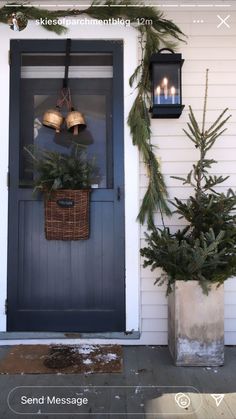 the front door is decorated for christmas with evergreens and lanterns on it's side