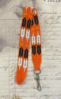 an orange beaded lanyard with black and white beads on it, sitting on top of a piece of paper