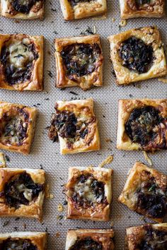 many small square pastries are arranged on a baking sheet