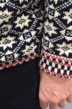 a close up of a person's hand wearing a sweater