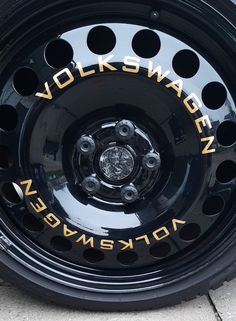 a black wheel with gold lettering on the side of it and some holes in the tire