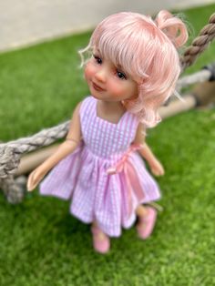 a doll is sitting on a swing in the grass