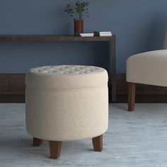 a white ottoman sitting next to a chair on top of a carpeted floor in front of a blue wall