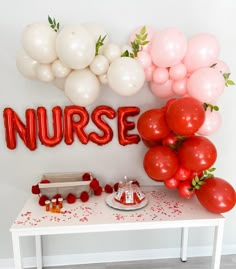 a table with balloons, cake and nurse's name on the wall behind it