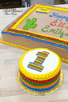 a birthday cake with the number one on it next to a large sheet cake covered in frosting