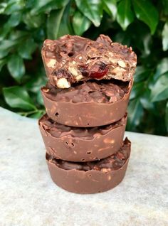 three pieces of chocolate with nuts and cranberries on top, stacked up against each other