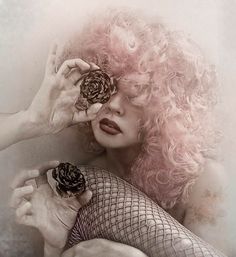 a woman with pink hair holding pine cones in front of her face and wearing fishnet stockings