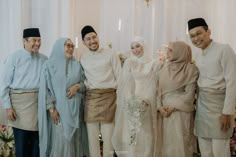 a group of people standing next to each other in front of a white wall with flowers