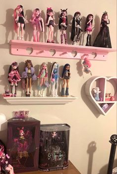 there are many barbie dolls on the shelf above the table and in front of them