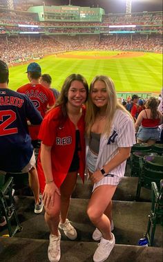 two women are posing for a photo in the stands at a baseball game with fans