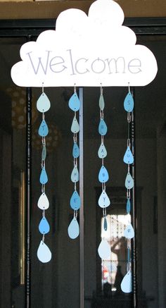 a welcome sign hanging from the side of a building with raindrops on it