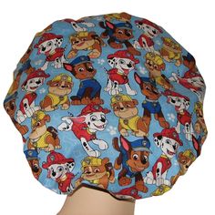 "Scrub Hats Paw Patrol fabric, blue cotton fabric with Marshall, Rubble andChase. None of the hats will be exactly the same as shown in photos due to pattern placement. First impressions matter with patients, put a smile on their face as you roll your patients in and out of the operating room in this scrub hat! Each scrub hat is hand-pleated with a comfortable seamless front band. The back features an elastic band with a cord stop toggle and pony bead to keep the toggle centered. All bouffant sc Marshall Paw Patrol Hat, Veterinarian Scrubs, Bloomsburg Pa, Bouffant Scrub Hat, Blue Cotton Fabric, Operating Room, Leftover Fabric, Scrub Hat, Pony Beads