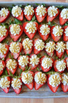 strawberries with white frosting and green leaves in a baking pan on a wooden table