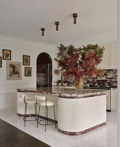 a large kitchen with marble counter tops and white cabinets, along with bar stools