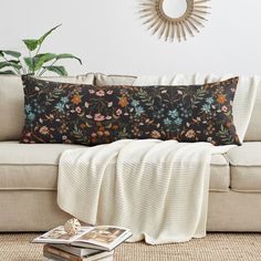 a living room with a white couch and black floral pillow on it's side