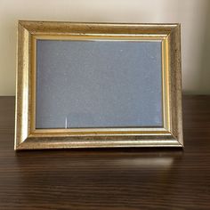 a gold frame sitting on top of a wooden table