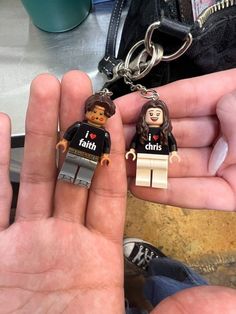 two legos are being held in the palm of someone's hand, one is wearing a keychain