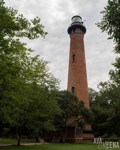 a tall light house surrounded by trees on a cloudy day