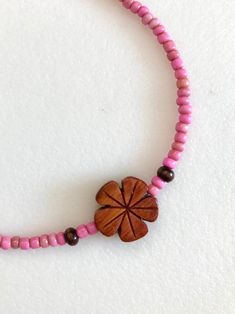 Darling little hand carved genuine Hawaiian Koa wood flower beaded with tiny dust rose pink vintage African glass beads and .925 sterling silver clasp. Koa wood plumeria flower is 1/2inch and beaded with 3-4mm vintage African trade beads in sweet dusty pink color. Necklace is 15 1/2 inches plus 2 Inch extension. Spring ring clasp and all findings are .925 sterling silver. Choker also available in aqua, orange and yellow. Pink Flower Beaded Necklaces For The Beach, Pink Flower Beaded Necklaces For Beach, Pink Beaded Necklace With Flower Pendant, Pink Wooden Beaded Necklaces For Gifts, Adjustable Pink Jewelry With Wooden Beads, Handmade Pink Flower Necklace, Pink Wooden Beads For Gifts, Pink Hand-strung Beaded Necklaces For Beach, Pink Beaded Flower Pendant Necklace