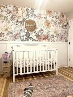 a baby's room with a floral wallpaper and white crib in the foreground