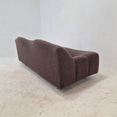 a brown couch sitting on top of a white floor next to a wall in a room