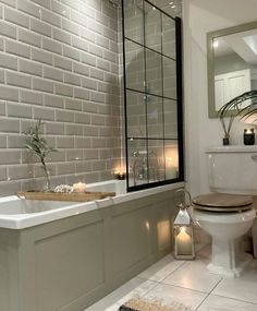 a bathroom with a white toilet and bathtub next to a window filled with candles