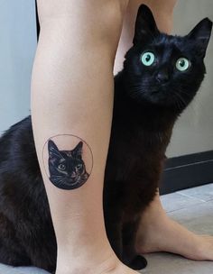 a black cat sitting next to a woman's leg with a tattoo on it