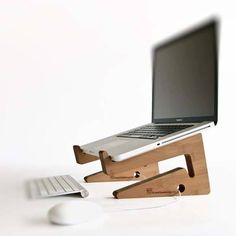 a laptop computer sitting on top of a wooden stand next to a mouse and keyboard