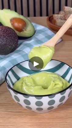 an avocado dip in a bowl with a wooden spoon next to it on a table