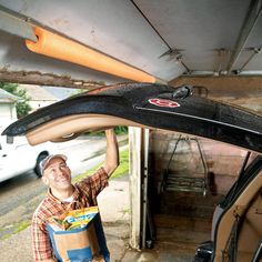 a man holding up a surfboard in the back of a car