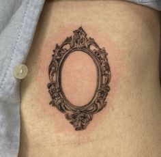 a woman's stomach with an oval frame tattoo on the side of her belly