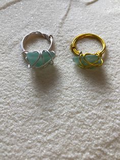 two rings sitting next to each other on top of a white surface, one is gold and the other is silver