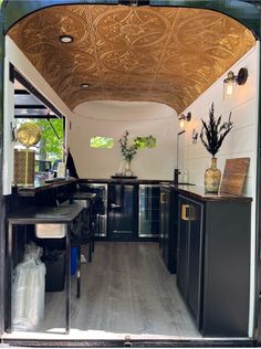 the inside of a camper with wood floors and black cabinetry is seen through an open door