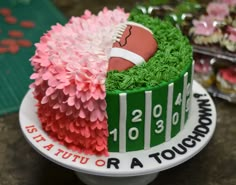 a football themed cake with pink flowers and green grass in the center on a plate