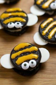 some cookies with yellow icing and eyes are on a wooden table next to each other