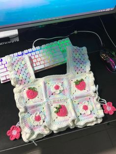 a crocheted bag sitting on top of a computer desk next to a keyboard